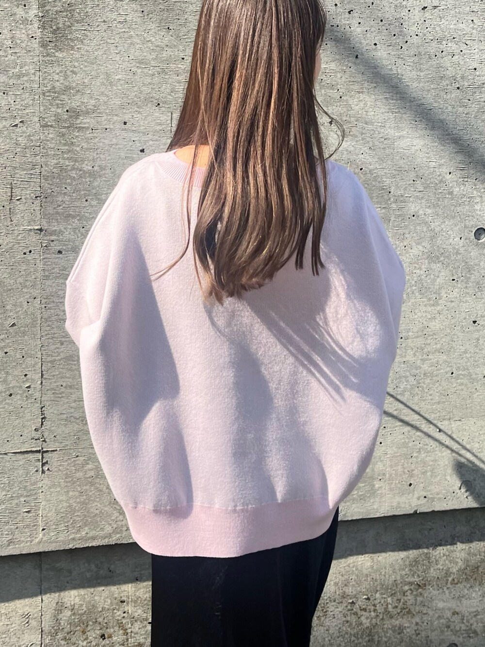 ピンク系のニット/セーター、ブラック系のスカート、ブラック系のショルダーバッグを着用したレディースの春コーディネートの5枚目の写真