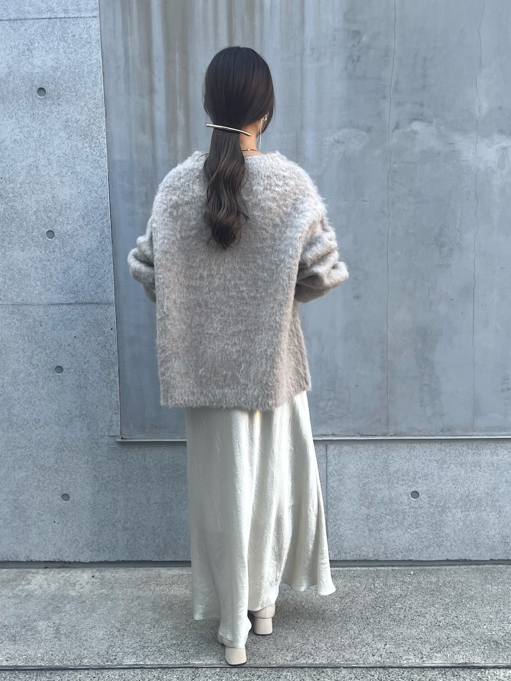 ベージュ系のニット/セーター、ホワイト系のスカート、ベージュ系のショルダーバッグを着用したレディースの冬コーディネートの3枚目の写真