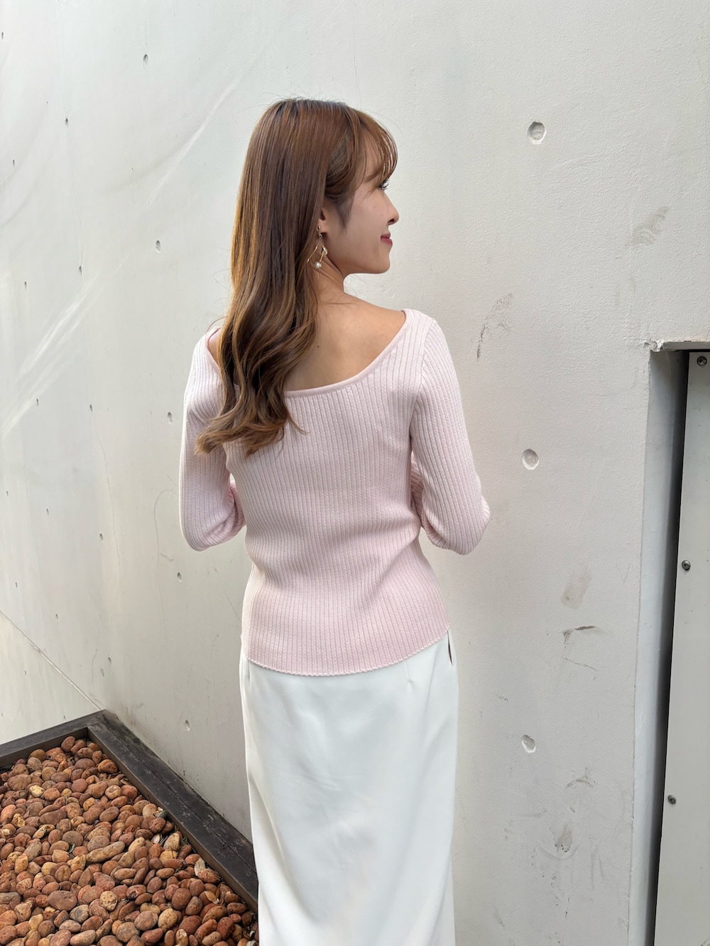 ピンク系のニット/セーター、ホワイト系のスカート、ホワイト系のブーツを着用したレディースの冬コーディネートの5枚目の写真