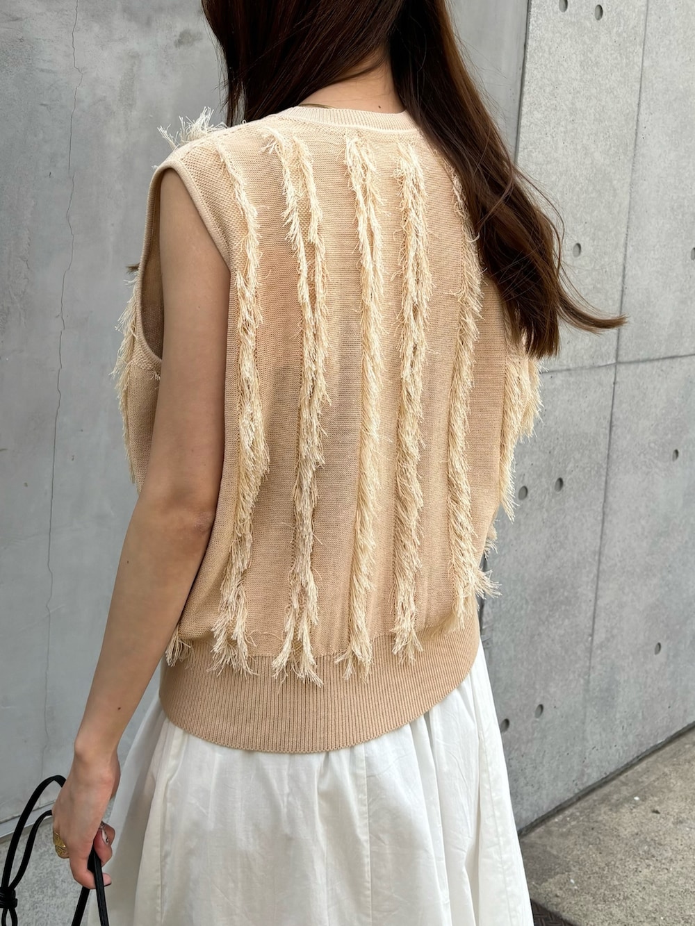 ベージュ系のニット/セーター、ホワイト系のスカート、ブラック系のショルダーバッグを着用したレディースの春コーディネートの8枚目の写真