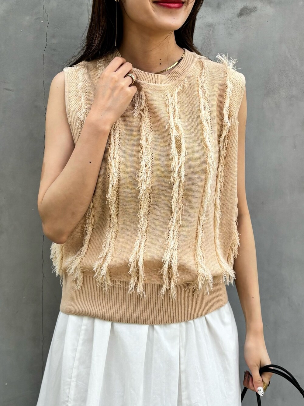 ベージュ系のニット/セーター、ホワイト系のスカート、ブラック系のショルダーバッグを着用したレディースの春コーディネートの4枚目の写真