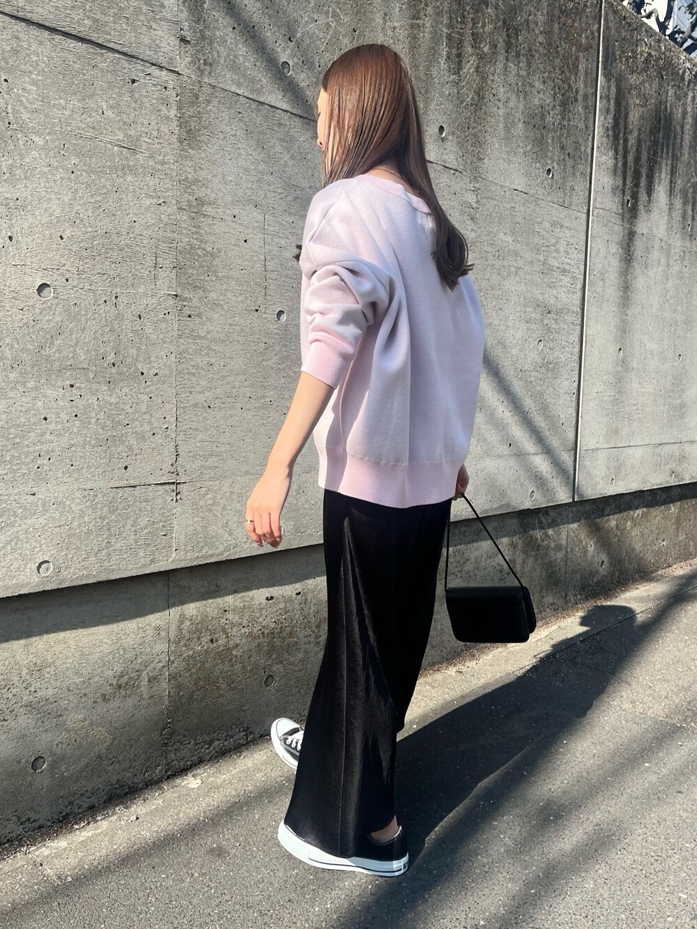 ピンク系のニット/セーター、ブラック系のスカート、ブラック系のショルダーバッグを着用したレディースの春コーディネートの6枚目の写真