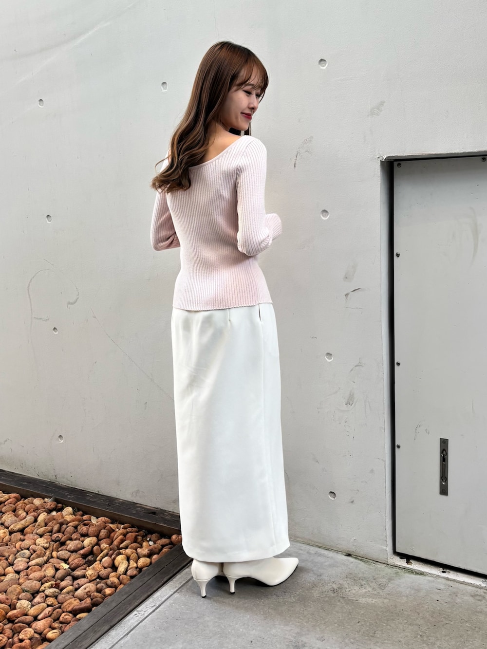ピンク系のニット/セーター、ホワイト系のスカート、ホワイト系のブーツを着用したレディースの冬コーディネートの2枚目の写真
