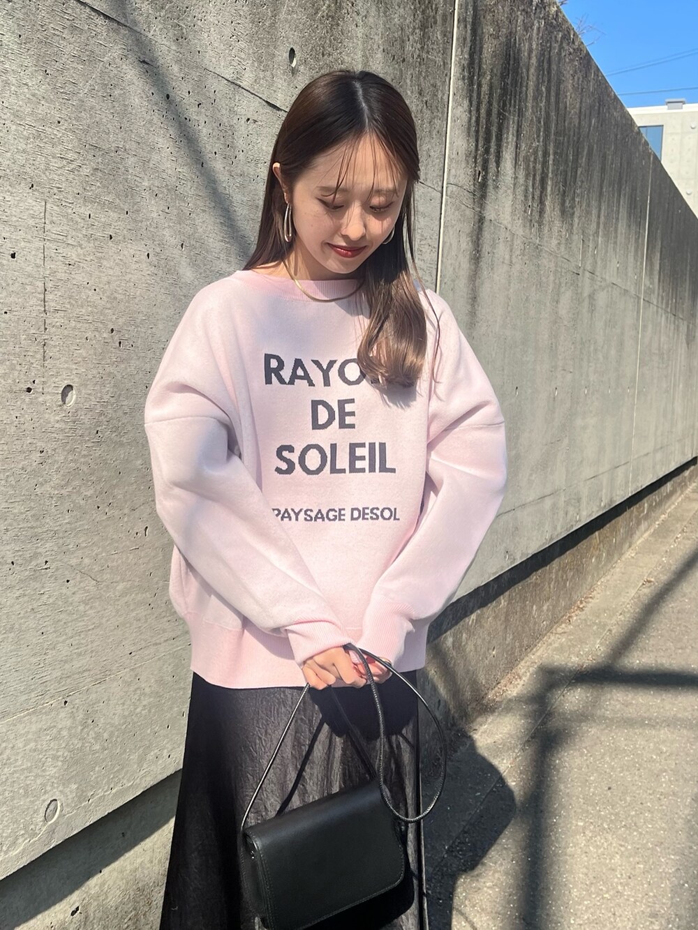 ピンク系のニット/セーター、ブラック系のスカート、ブラック系のショルダーバッグを着用したレディースの春コーディネートの2枚目の写真