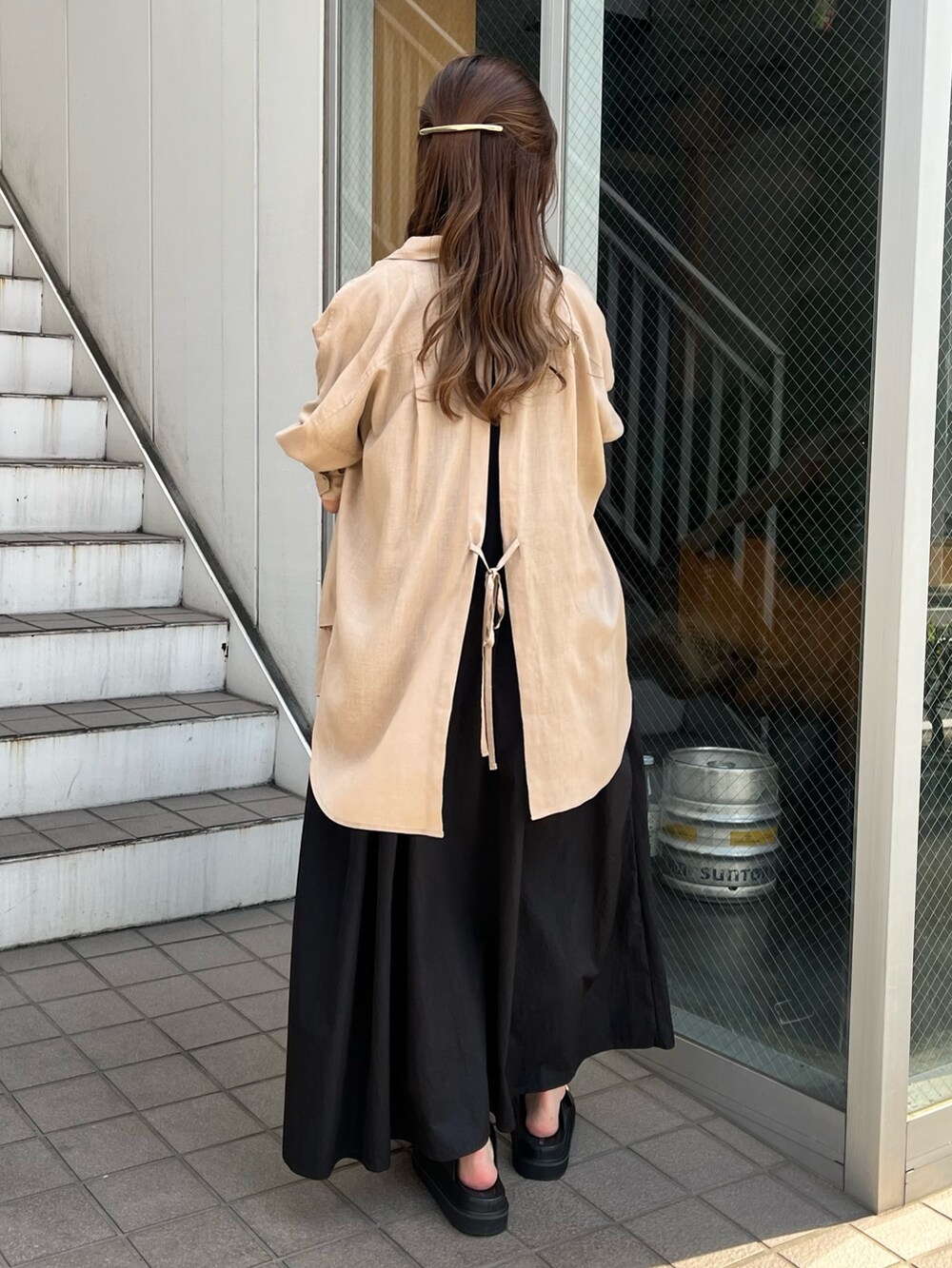 ブラック系のワンピース、ベージュ系のシャツ/ブラウス、ブラック系のサンダルを着用したレディースの春コーディネートの4枚目の写真