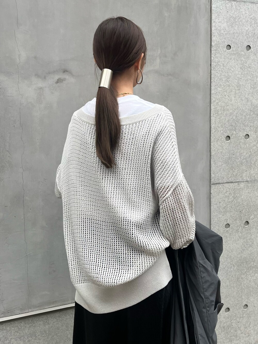 グレー系のニット/セーター、ブラック系のスカート、ホワイト系のパンプスを着用したレディースの春コーディネートの5枚目の写真