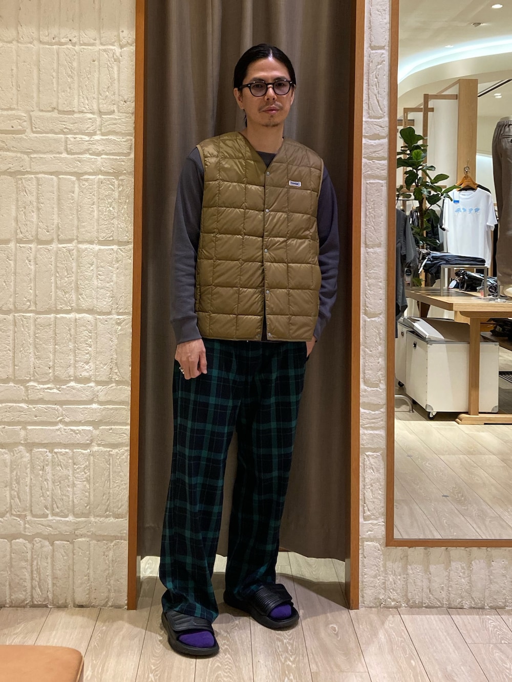 ベージュ系のダウンベスト、グレー系のTシャツ/カットソー、グリーン系のその他パンツを着用したメンズの秋コーディネートの3枚目の写真