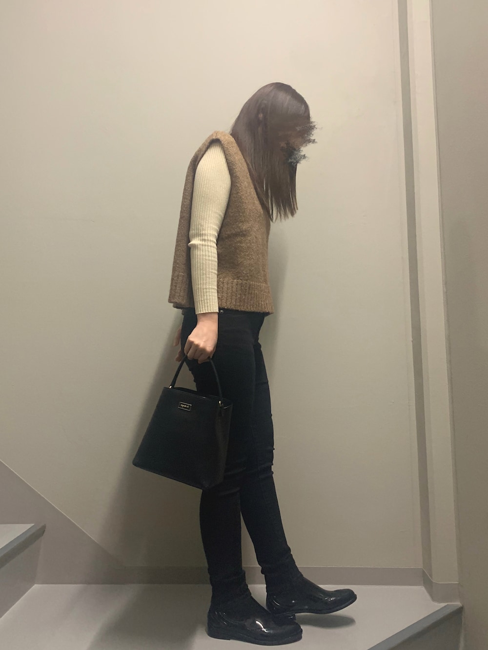 ブラウン系のベスト、ブラック系のハンドバッグ、ブラック系のデニムパンツを着用したレディースの冬コーディネートの3枚目の写真