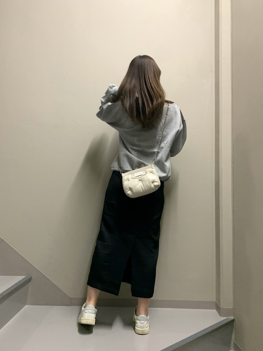 ブラック系のスカート、ホワイト系のスニーカー、ホワイト系のバッグを着用したレディースの冬コーディネートの4枚目の写真