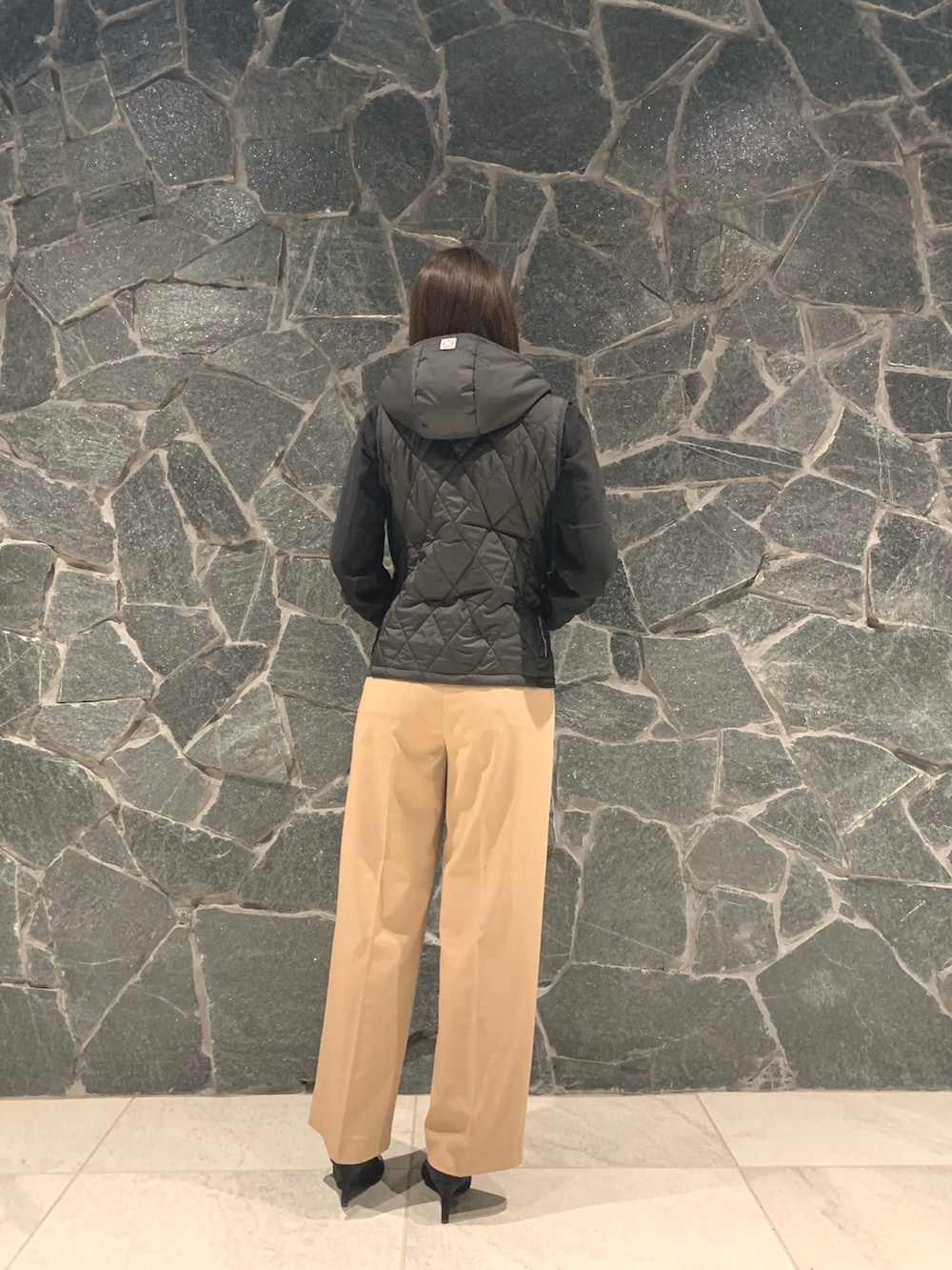 グレー系のパンツ、ブラック系のハンドバッグ、ブラック系のパンプスを着用したレディースの秋コーディネートの3枚目の写真