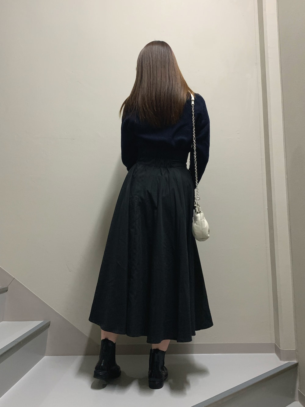 ブラック系のスカート、ブラック系のレインシューズ、ホワイト系のバッグを着用したレディースの冬コーディネートの3枚目の写真