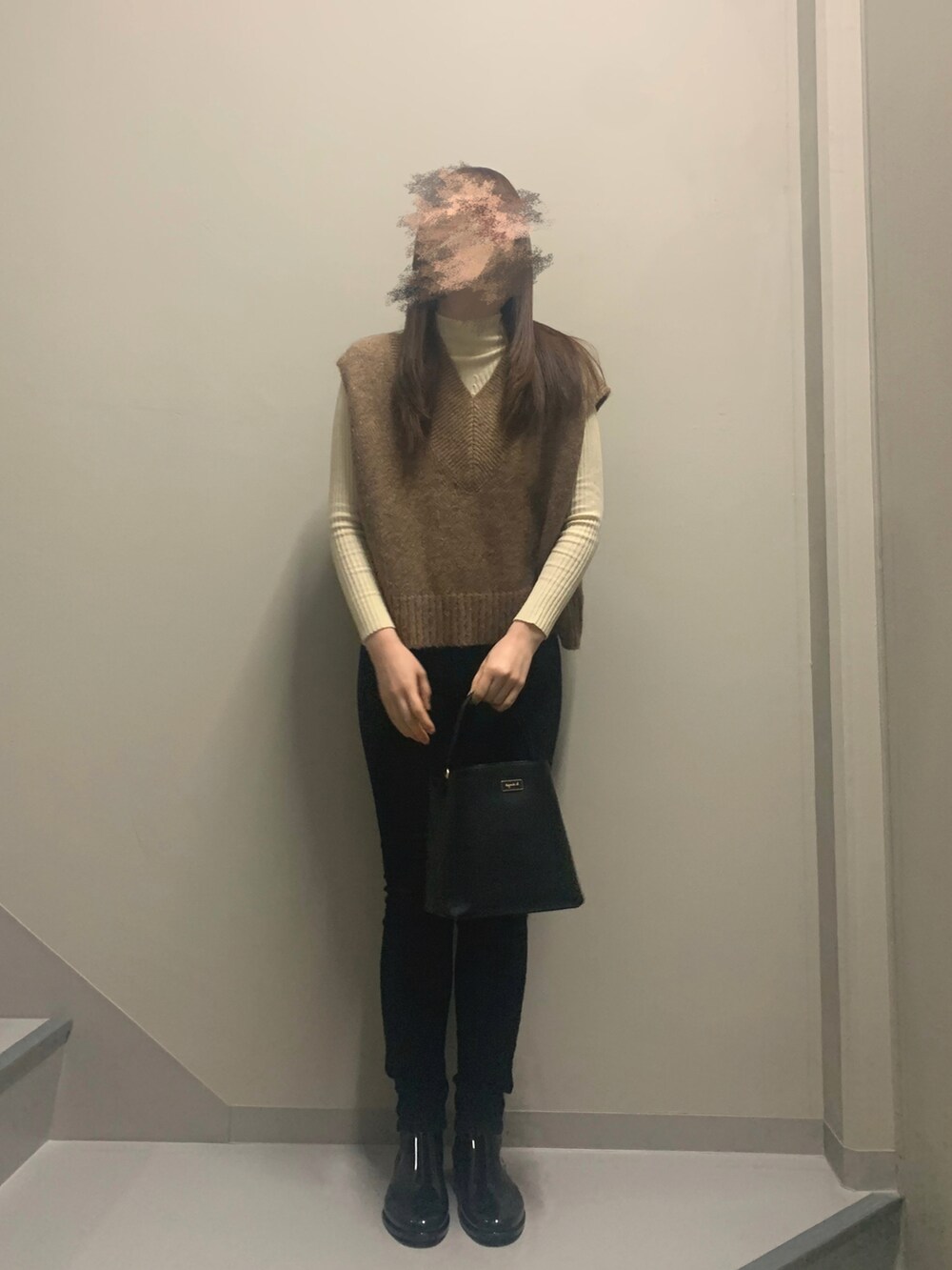 ブラウン系のベスト、ブラック系のハンドバッグ、ブラック系のデニムパンツを着用したレディースの冬コーディネートの2枚目の写真