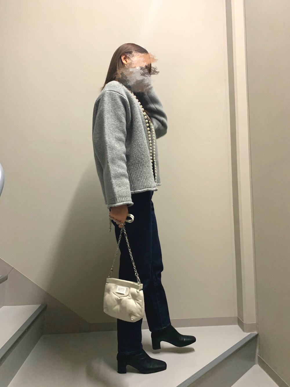 ブルー系のデニムパンツ、ホワイト系のバッグ、ブラウン系のブーツを着用したレディースの冬コーディネートの2枚目の写真