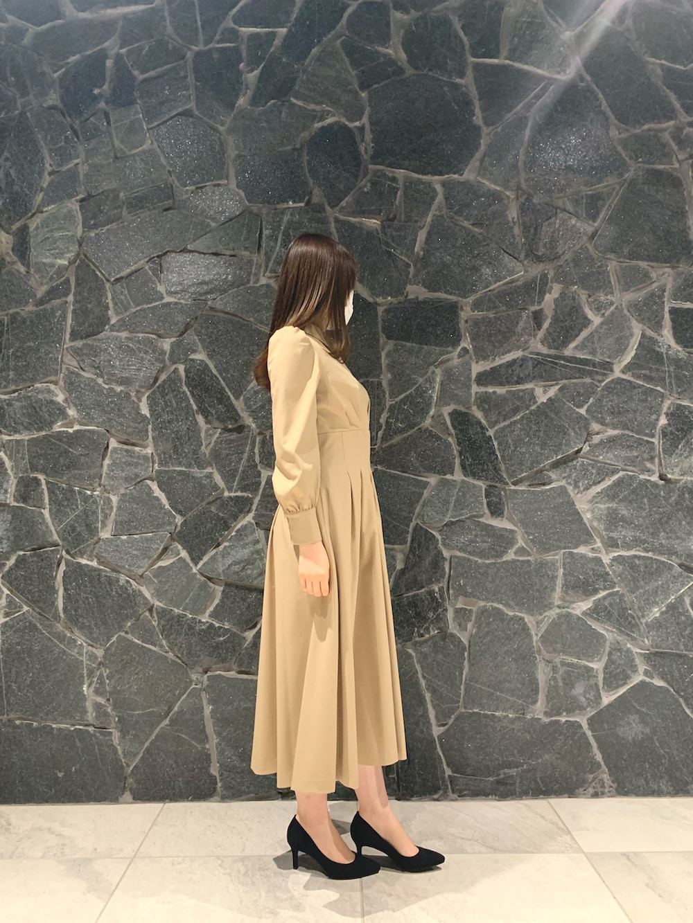 ベージュ系のワンピース、ブラック系のハンドバッグ、ブラック系のパンプスを着用したレディースの冬コーディネートの2枚目の写真