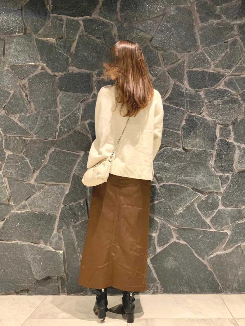 ホワイト系のニット/セーター、ブラウン系のスカート、ブラウン系のブーツを着用したレディースの冬コーディネートの3枚目の写真