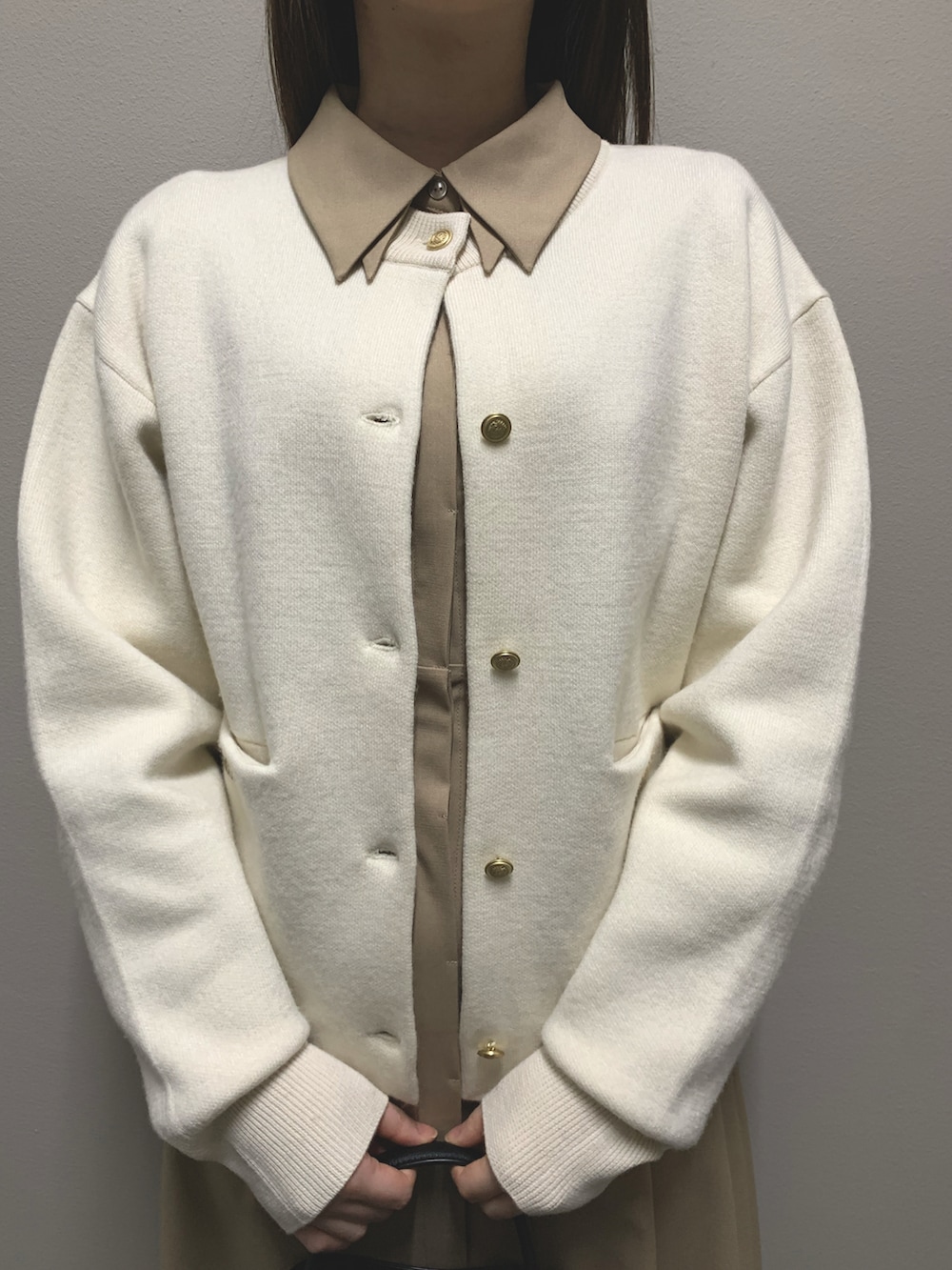 ホワイト系のカーディガン/ボレロ、ベージュ系のワンピース、ブラック系のハンドバッグを着用したレディースの冬コーディネートの4枚目の写真