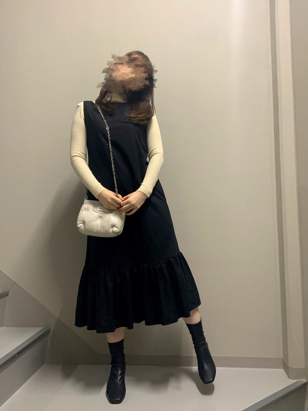 ブラック系のワンピース/ドレス、ベージュ系のニット/セーター、ホワイト系のバッグを着用したレディースの冬コーディネートの2枚目の写真