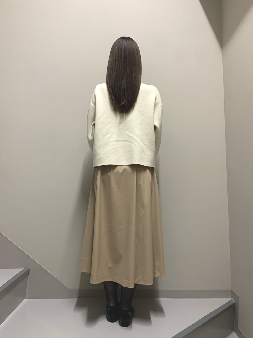 ホワイト系のカーディガン/ボレロ、ベージュ系のワンピース、ブラック系のハンドバッグを着用したレディースの冬コーディネートの3枚目の写真