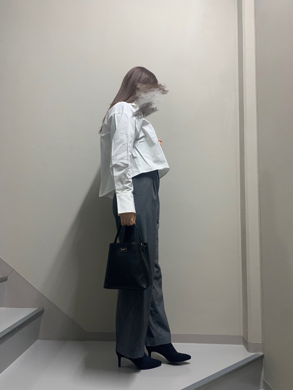 グレー系のパンツ、ブラック系のパンプス、ブラック系のハンドバッグを着用したレディースの冬コーディネートの2枚目の写真