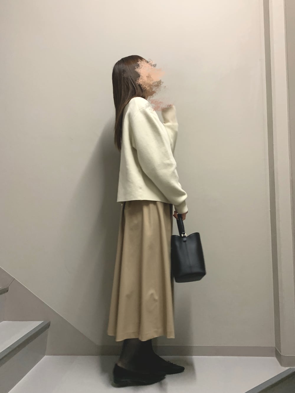 ホワイト系のカーディガン/ボレロ、ベージュ系のワンピース、ブラック系のハンドバッグを着用したレディースの冬コーディネートの2枚目の写真