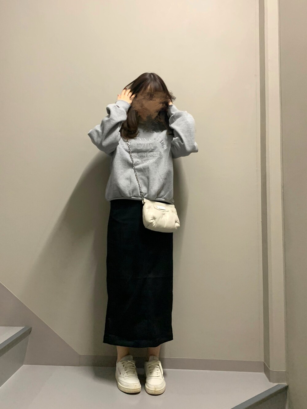 ブラック系のスカート、ホワイト系のスニーカー、ホワイト系のバッグを着用したレディースの冬コーディネートの2枚目の写真