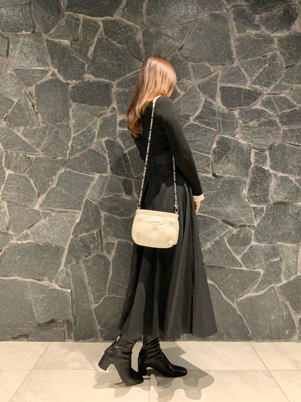 ブラック系のニット/セーター、ブラック系のスカート、ブラウン系のブーツを着用したレディースの冬コーディネートの2枚目の写真