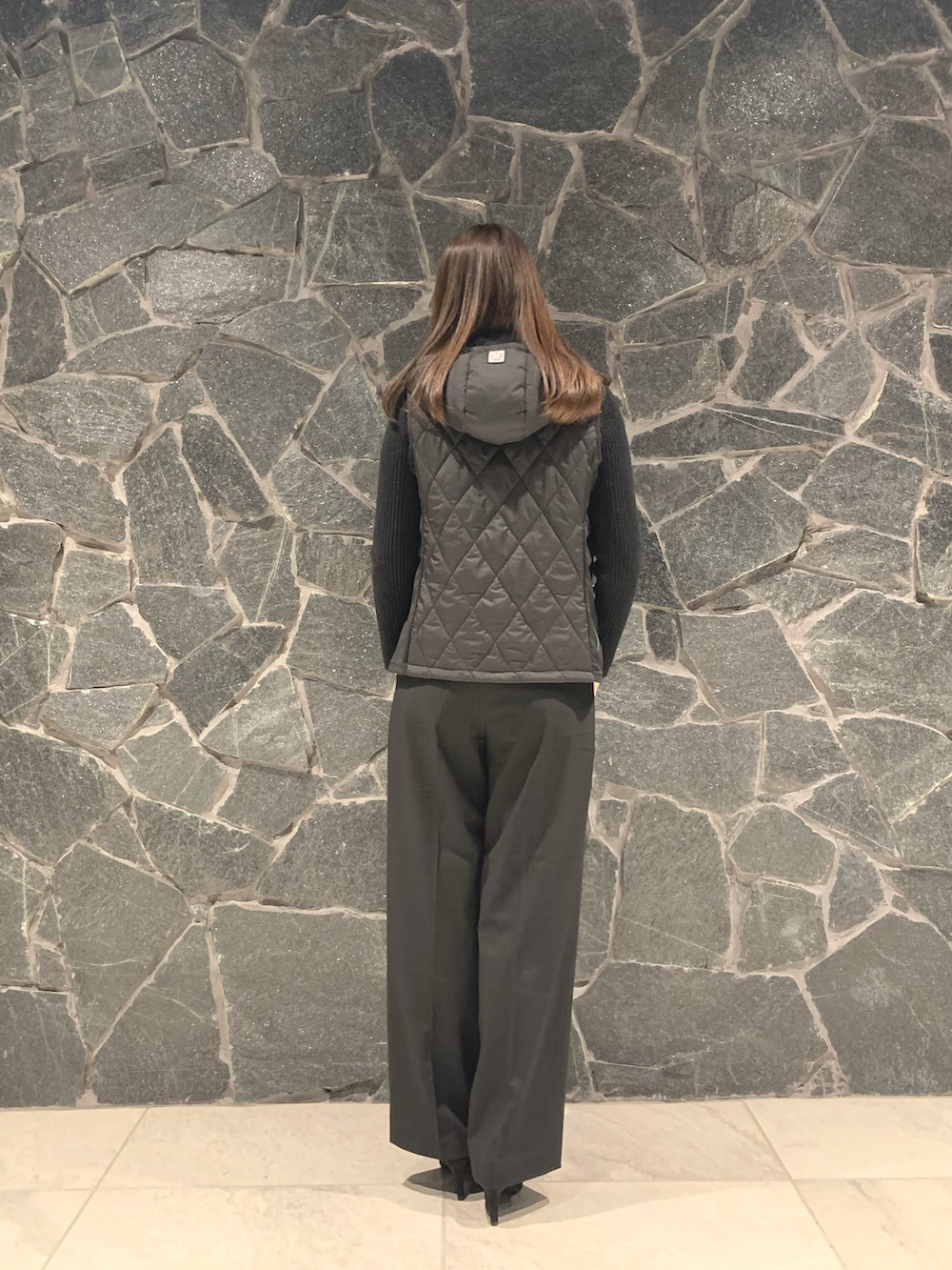 グレー系のパンツ、ブラック系のパンプス、ベージュ系のトートバッグを着用したレディースの冬コーディネートの3枚目の写真