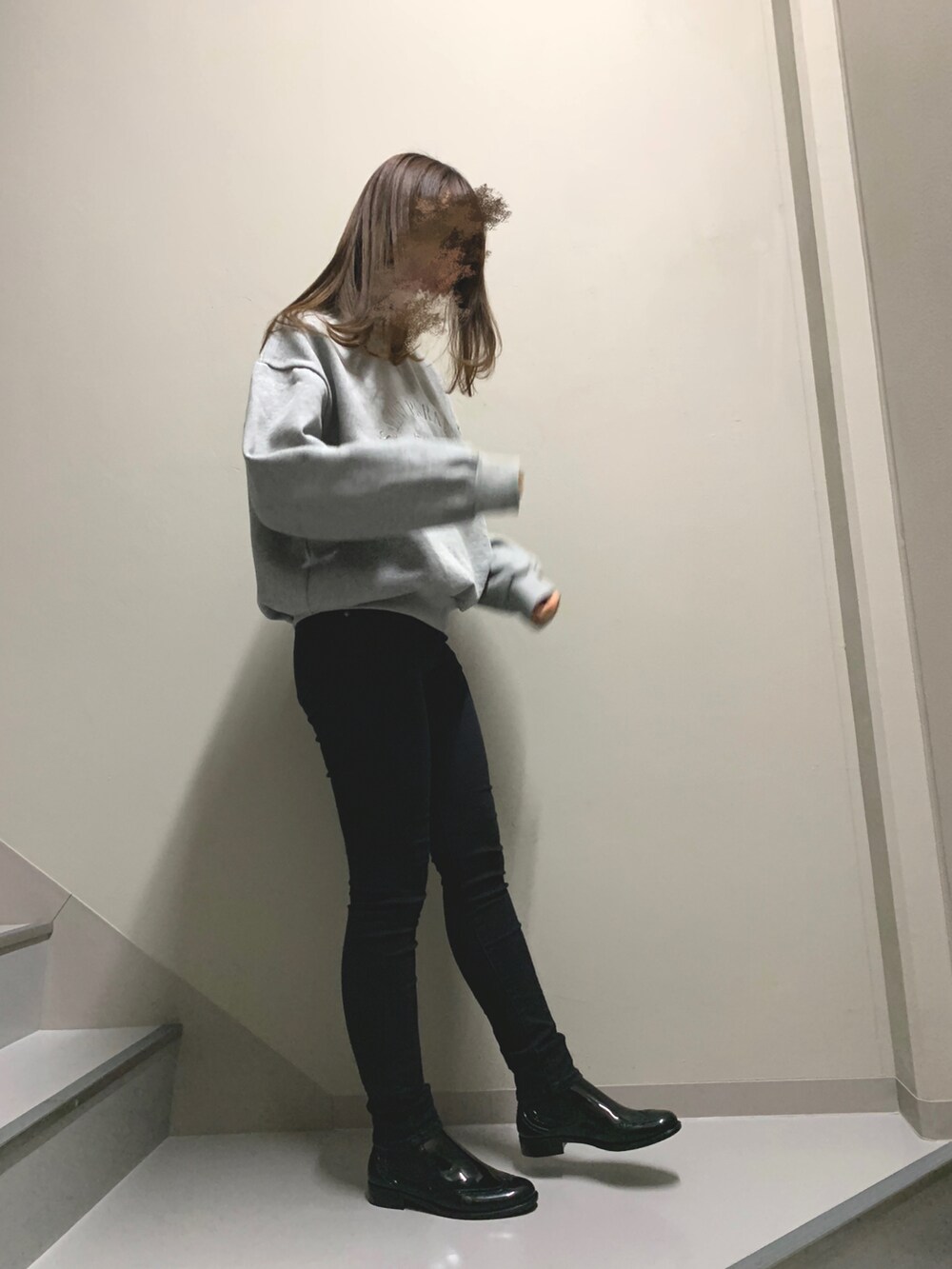 グレー系のスウェット、ブラック系のニット/セーター、ブラック系のデニムパンツを着用したレディースの冬コーディネートの2枚目の写真