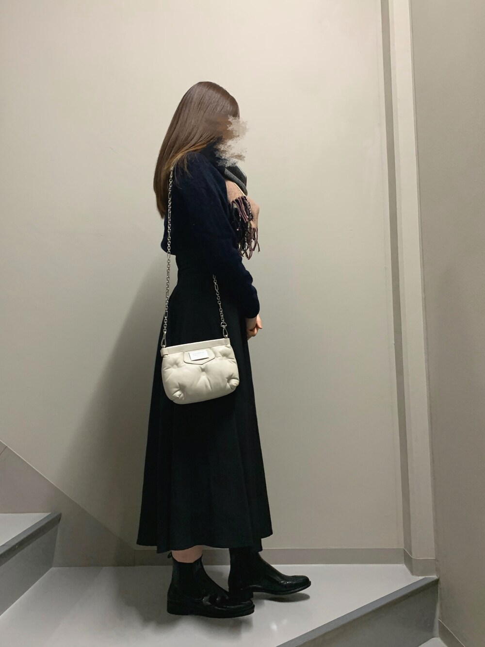 ブラック系のスカート、ブラック系のレインシューズ、ホワイト系のバッグを着用したレディースの冬コーディネートの2枚目の写真