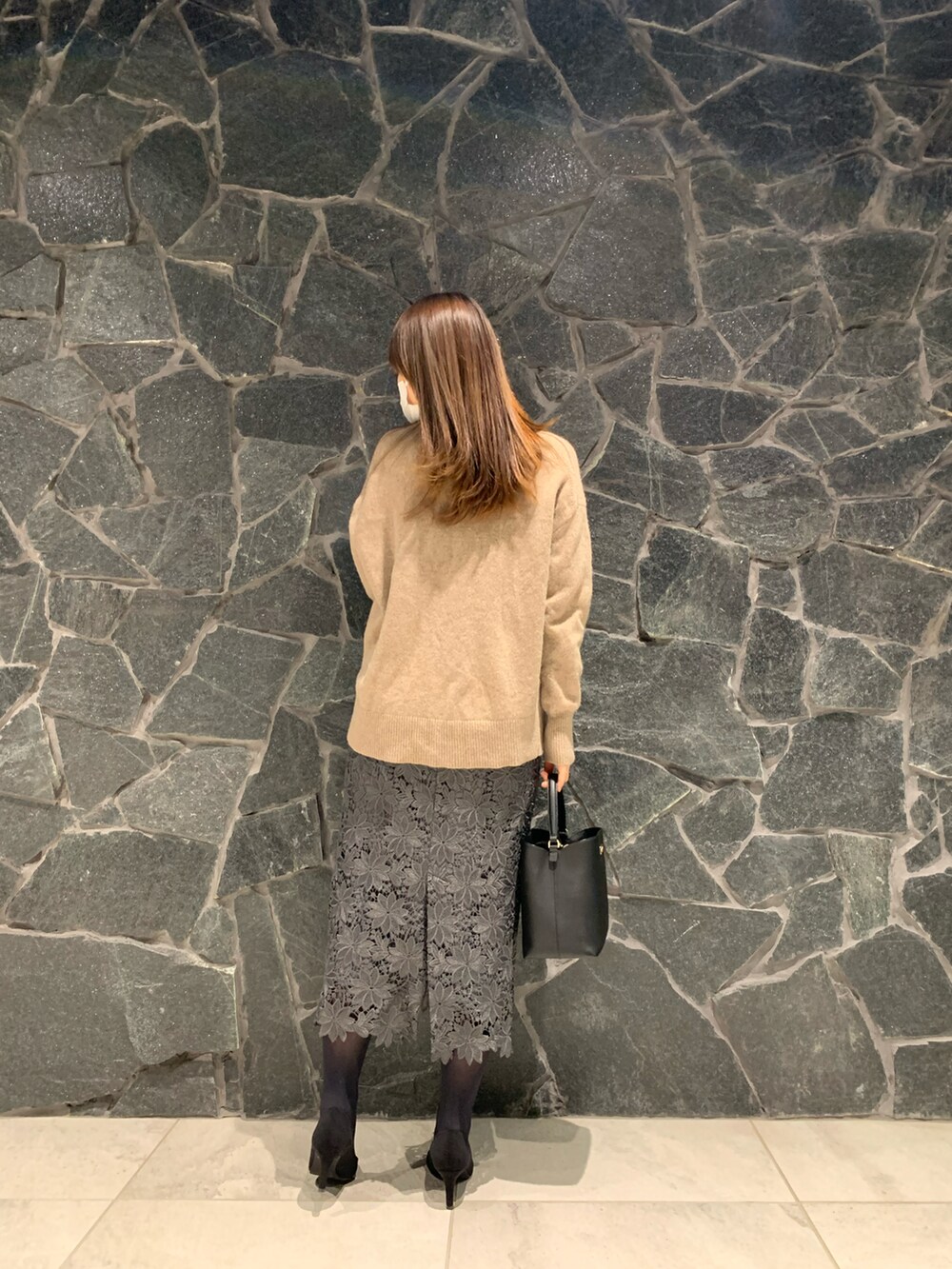 ブラック系のハンドバッグ、ベージュ系のニット/セーター、ブラウン系のスカートを着用したレディースの冬コーディネートの3枚目の写真