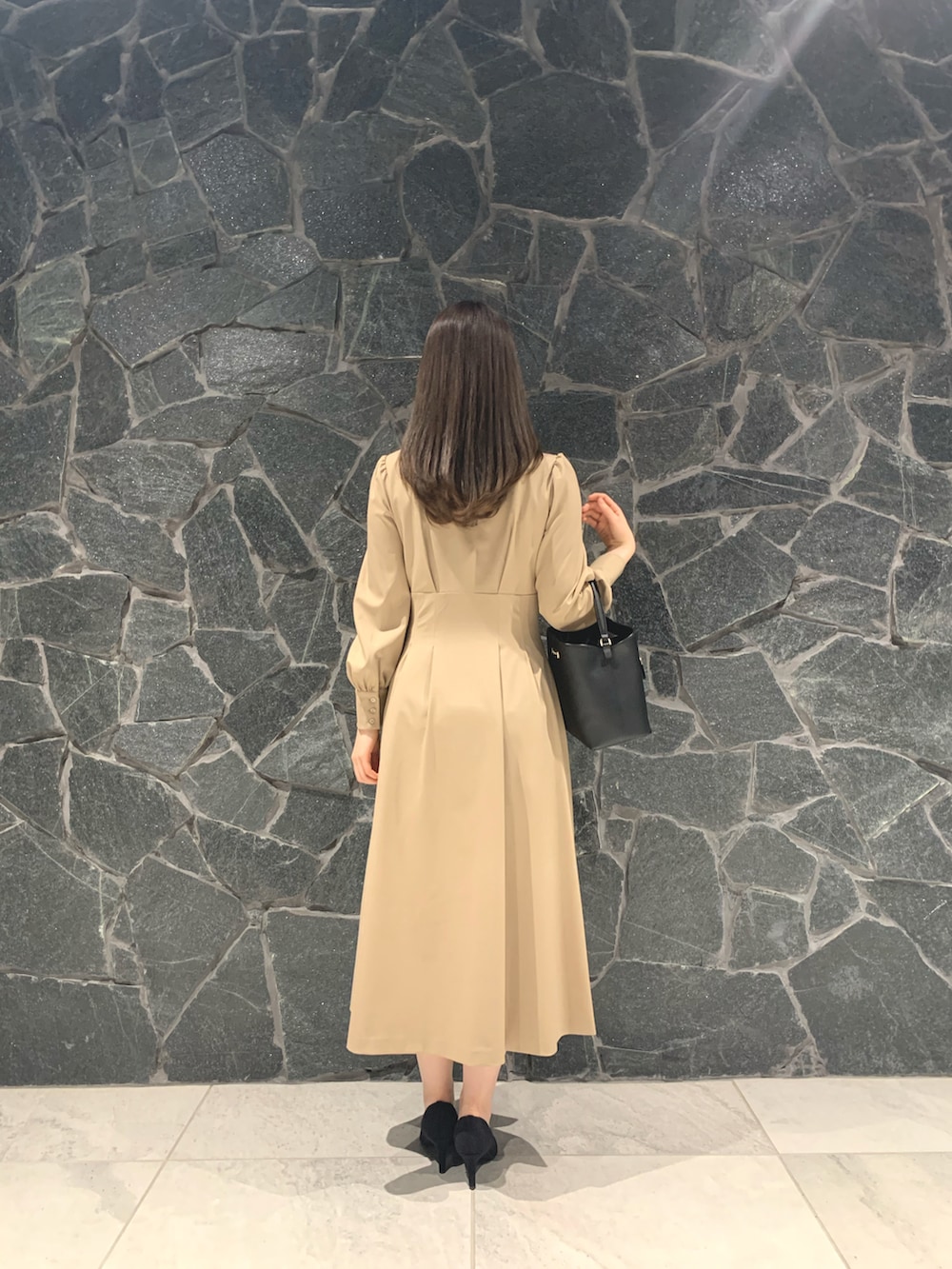 ベージュ系のワンピース、ブラック系のハンドバッグ、ブラック系のパンプスを着用したレディースの冬コーディネートの3枚目の写真