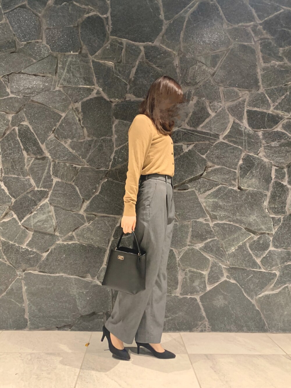 グレー系のパンツ、ベージュ系のカーディガン/ボレロ、ブラック系のハンドバッグを着用したレディースの秋コーディネートの2枚目の写真