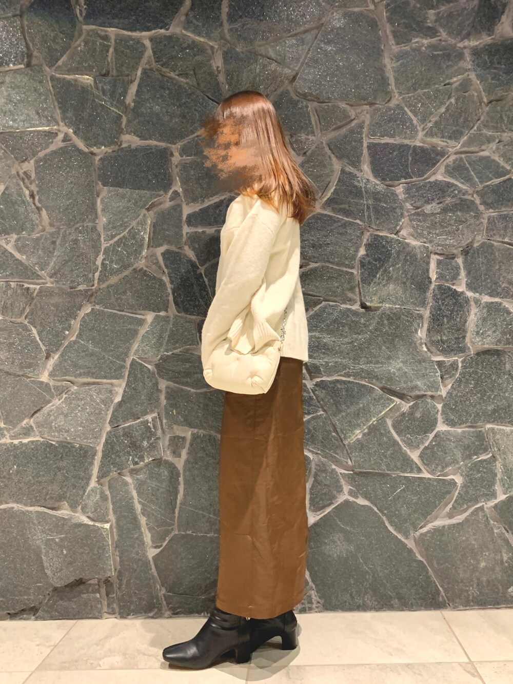 ホワイト系のニット/セーター、ブラウン系のスカート、ブラウン系のブーツを着用したレディースの冬コーディネートの2枚目の写真