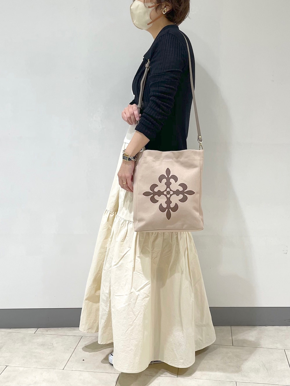 ブラック系のカーディガン/ボレロ、ベージュ系のトートバッグ、ホワイト系のスカートを着用したレディースの春コーディネートの2枚目の写真