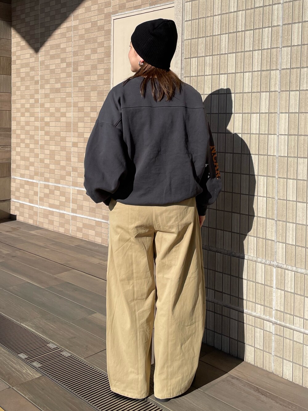 ベージュ系のチノパンツ、グレー系のスウェット、ブラック系のニットキャップ/ビーニーを着用したレディースの冬コーディネートの4枚目の写真