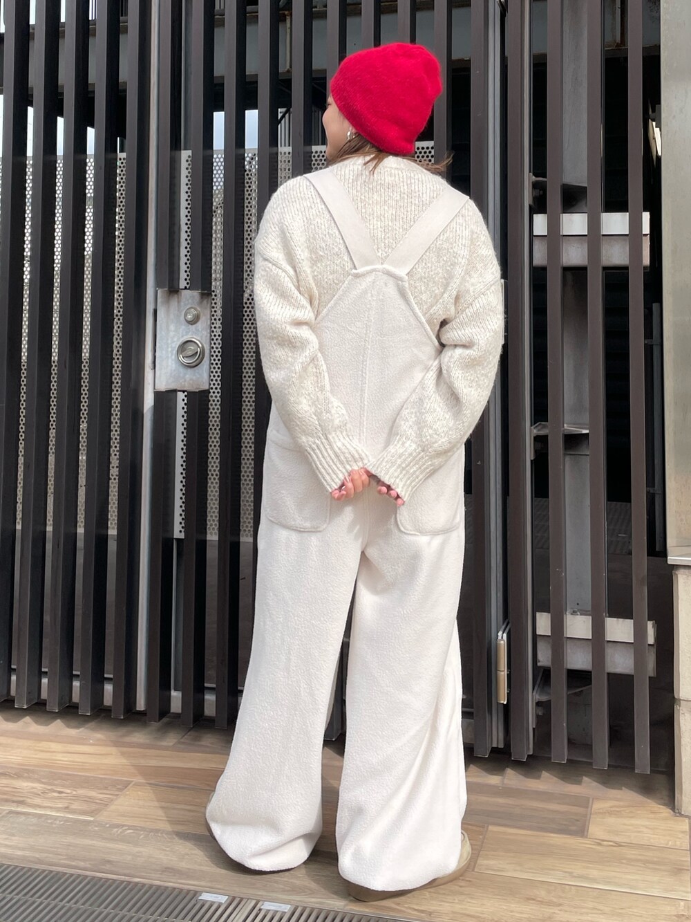 ホワイト系のニット/セーター、ホワイト系のサロペット/オーバーオール、レッド系のニットキャップ/ビーニーを着用したレディースの秋コーディネートの3枚目の写真