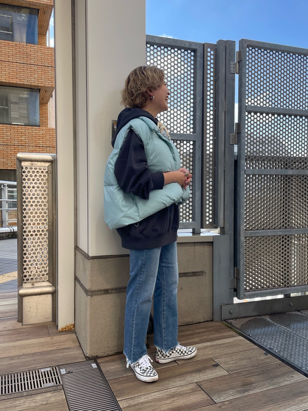 ブルー系のダウンベスト、グレー系のパーカー、ブルー系のデニムパンツを着用したレディースの秋コーディネートの2枚目の写真