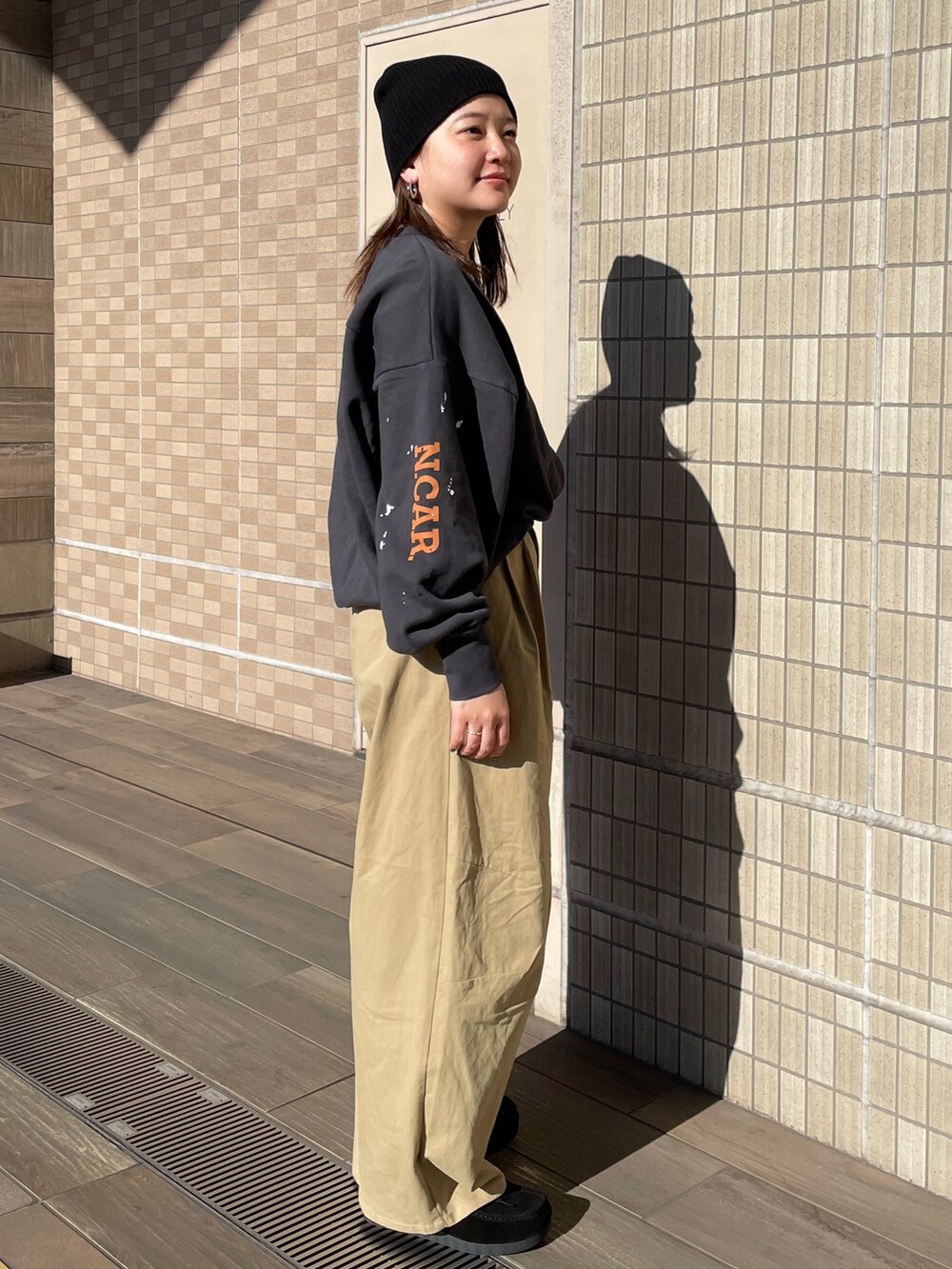 ベージュ系のチノパンツ、グレー系のスウェット、ブラック系のニットキャップ/ビーニーを着用したレディースの冬コーディネートの3枚目の写真