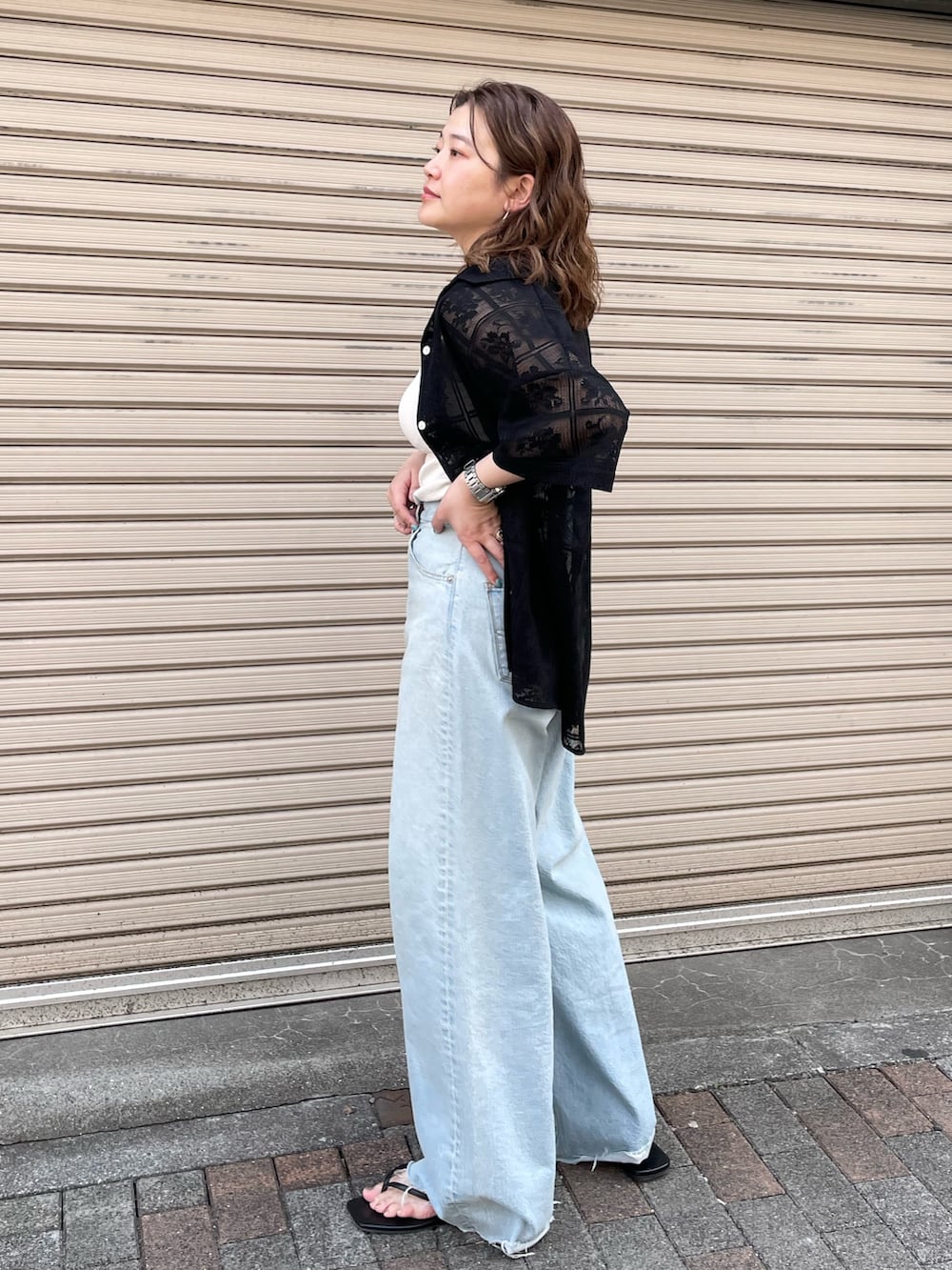 ブラック系のシャツ/ブラウス、ホワイト系のキャミソール、ブルー系のデニムパンツを着用したレディースの春コーディネートの2枚目の写真