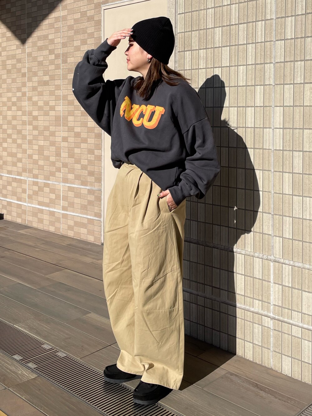 ベージュ系のチノパンツ、グレー系のスウェット、ブラック系のニットキャップ/ビーニーを着用したレディースの冬コーディネートの2枚目の写真