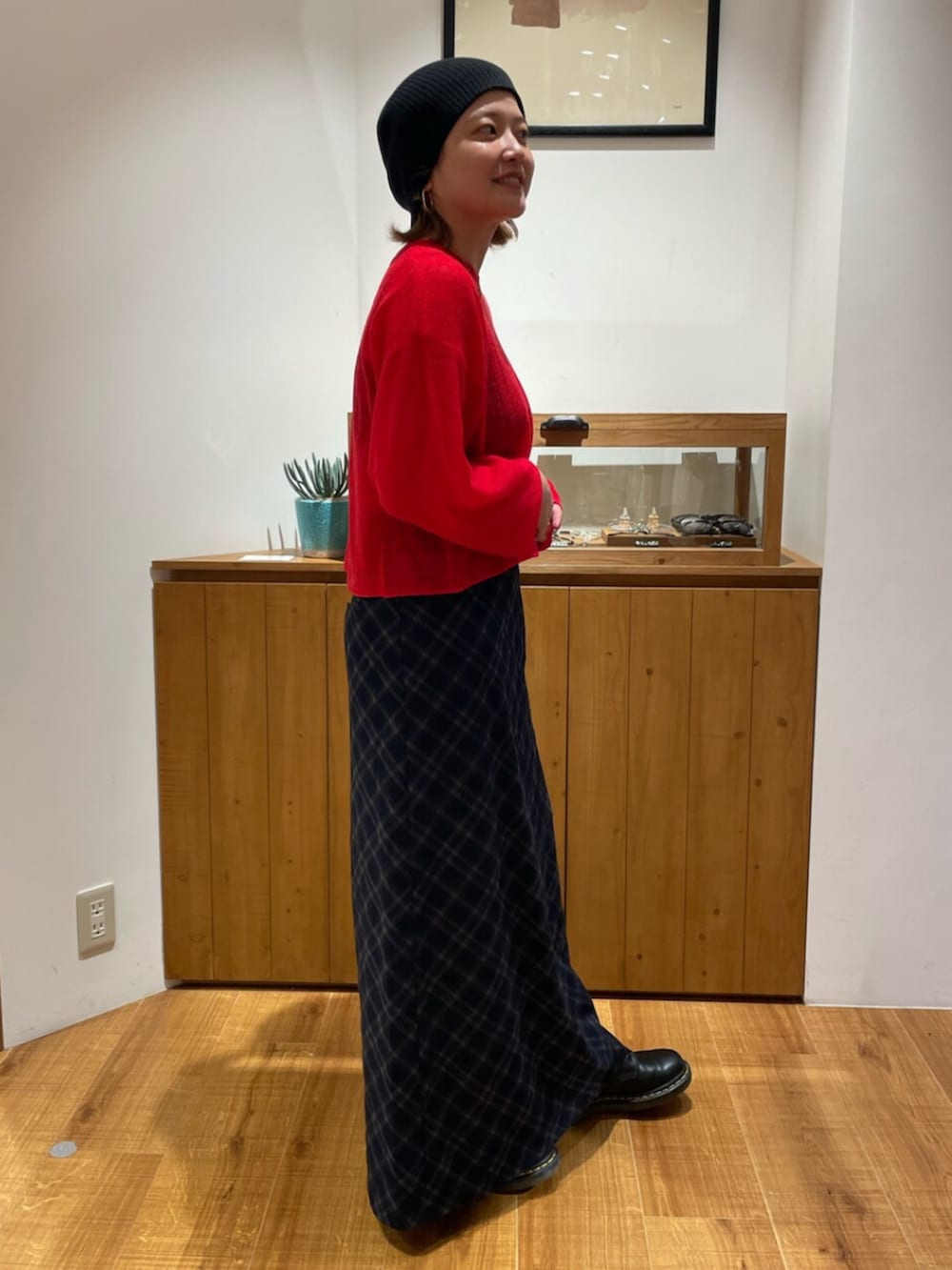 レッド系のニット/セーター、ブルー系のスカートを着用したレディースの秋コーディネートの2枚目の写真