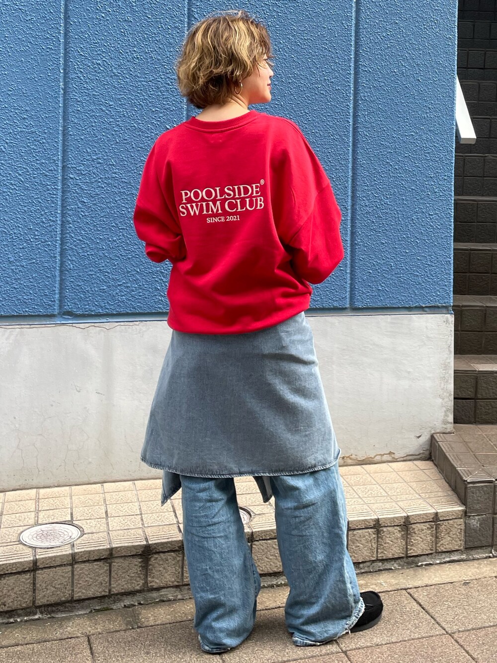 レッド系のスウェット、ブルー系のシャツ/ブラウス、ブルー系のデニムパンツを着用したレディースの秋コーディネートの3枚目の写真