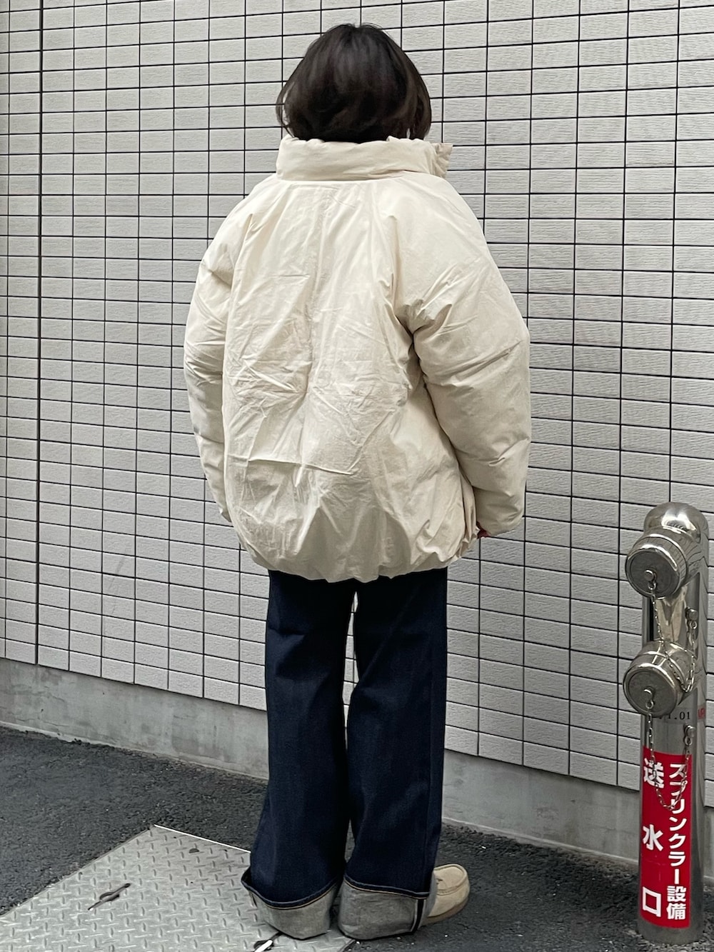 ホワイト系のブルゾン、グレー系のカーディガン/ボレロ、ブルー系のデニムパンツを着用したレディースの冬コーディネートの3枚目の写真