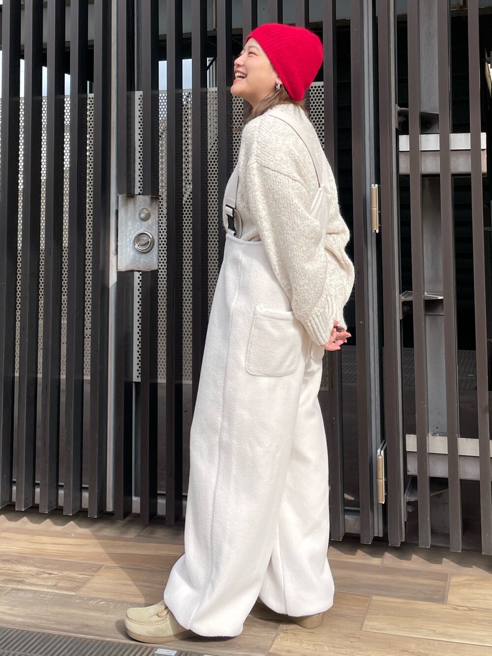 ホワイト系のニット/セーター、ホワイト系のサロペット/オーバーオール、レッド系のニットキャップ/ビーニーを着用したレディースの秋コーディネートの2枚目の写真