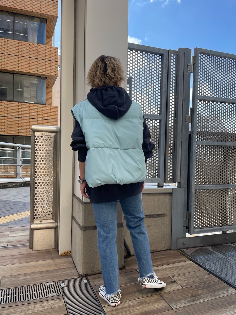 ブルー系のダウンベスト、グレー系のパーカー、ブルー系のデニムパンツを着用したレディースの秋コーディネートの3枚目の写真