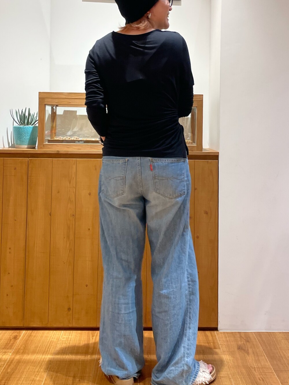 ブラック系のTシャツ/カットソー、ブルー系のデニムパンツ、ホワイト系のサンダルを着用したレディースの春コーディネートの4枚目の写真