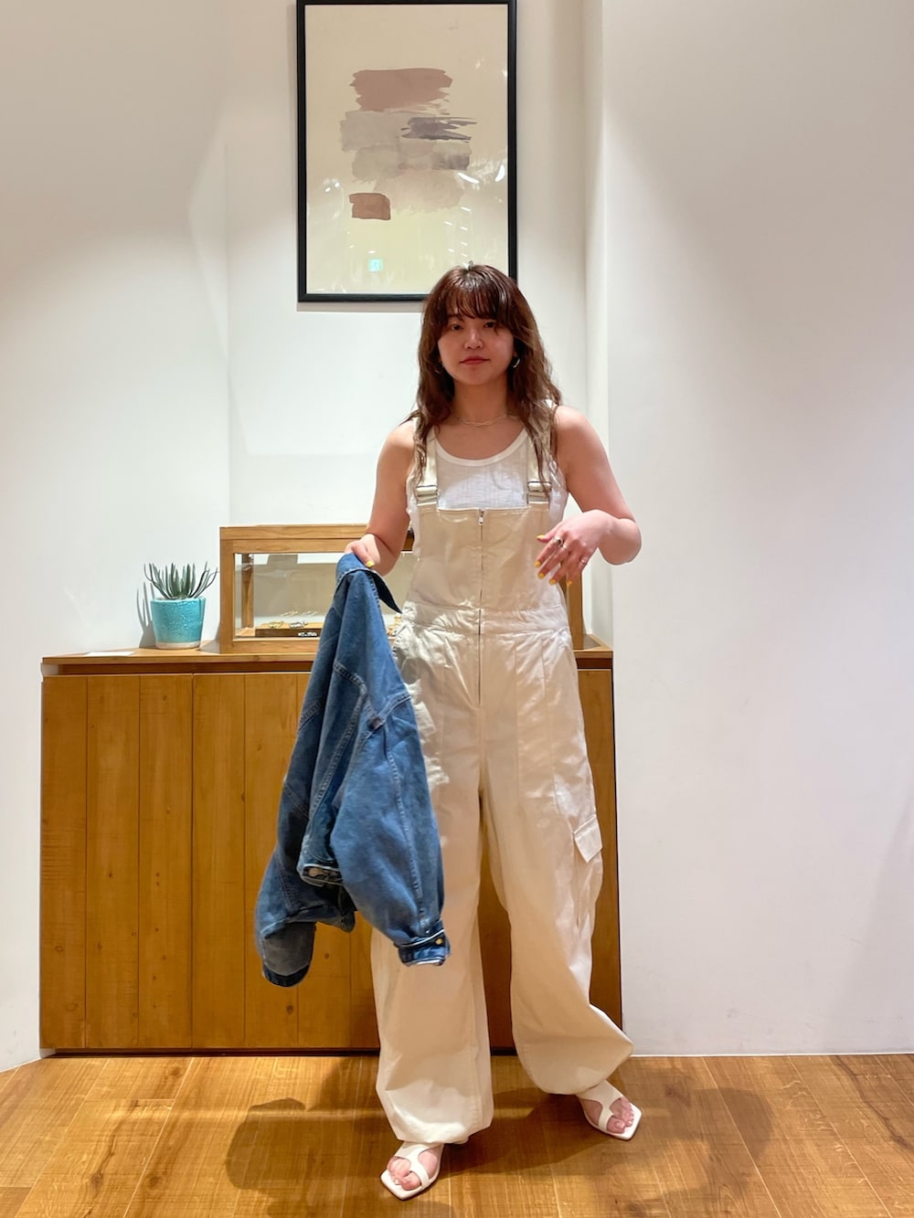ブルー系のデニムジャケット、ホワイト系のつなぎ/オールインワン、ホワイト系のサンダルを着用したレディースの春コーディネートの4枚目の写真