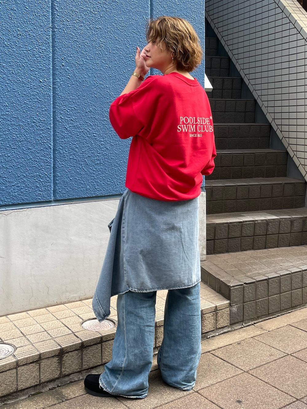 レッド系のスウェット、ブルー系のシャツ/ブラウス、ブルー系のデニムパンツを着用したレディースの秋コーディネートの2枚目の写真
