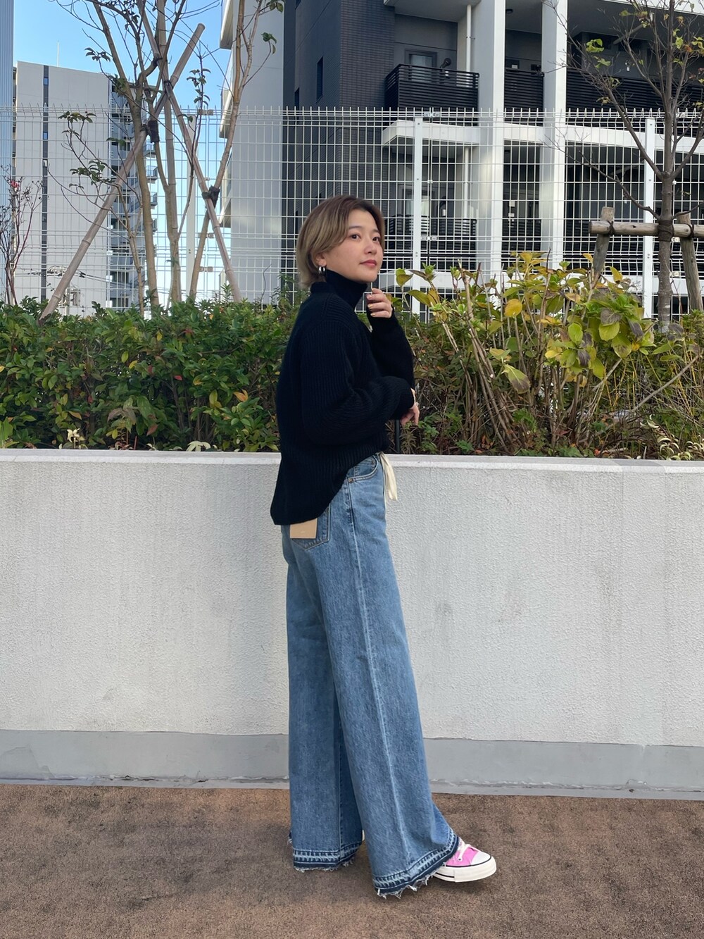 ブラック系のニット/セーター、ブルー系のデニムパンツ、ピンク系のスニーカーを着用したレディースの冬コーディネートの2枚目の写真