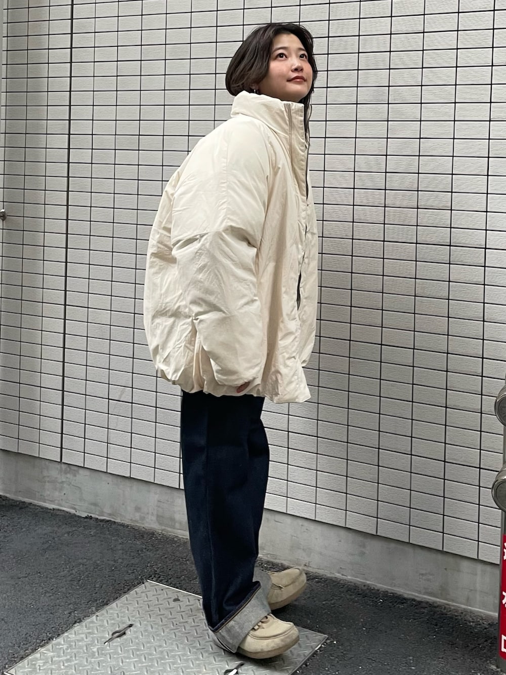 ホワイト系のブルゾン、グレー系のカーディガン/ボレロ、ブルー系のデニムパンツを着用したレディースの冬コーディネートの2枚目の写真